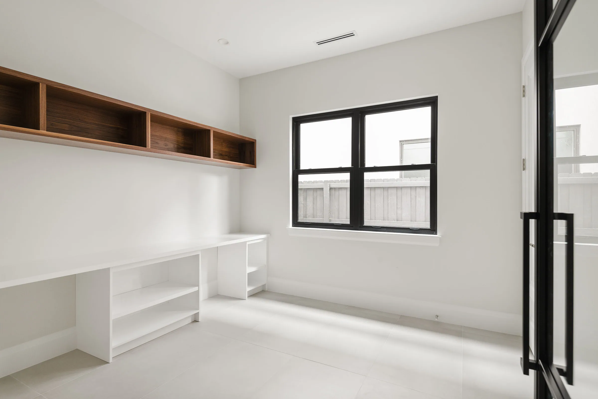 Built-in desk and shelving beneath a high window.