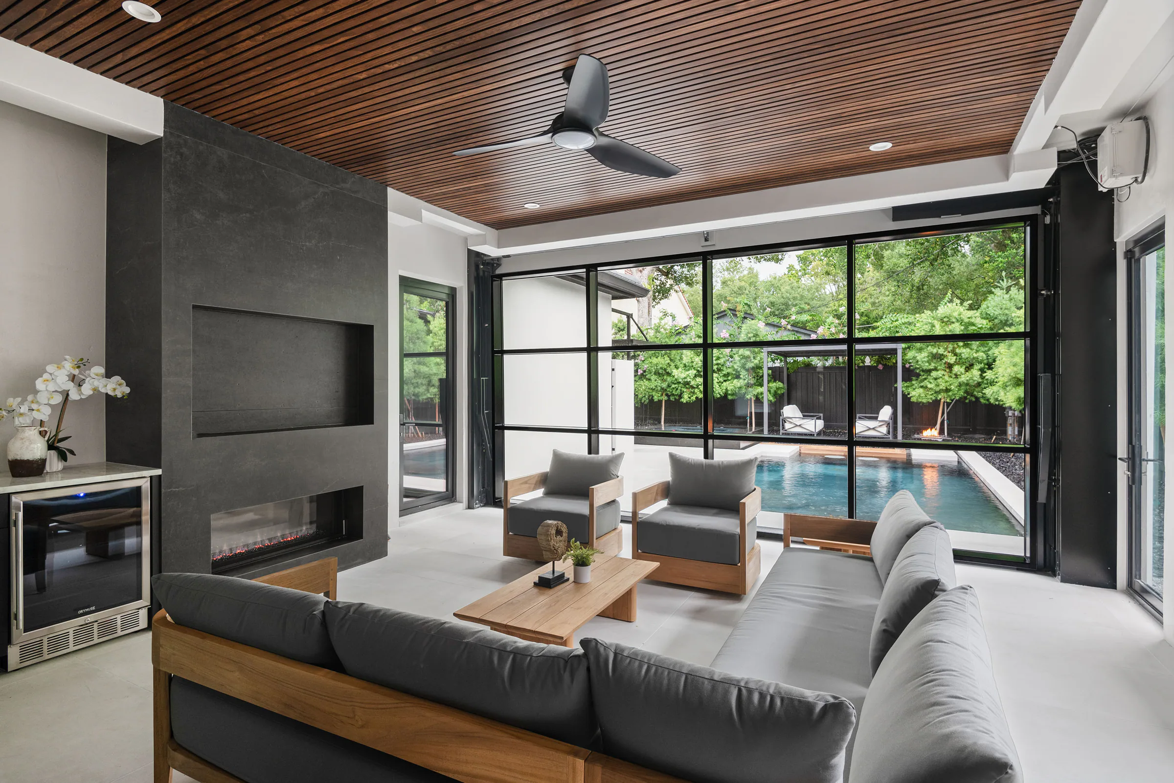 Covered outdoor lounge beneath a dark wood ceiling. New Hampshire, a custom home by Rare Builders in Orlando.