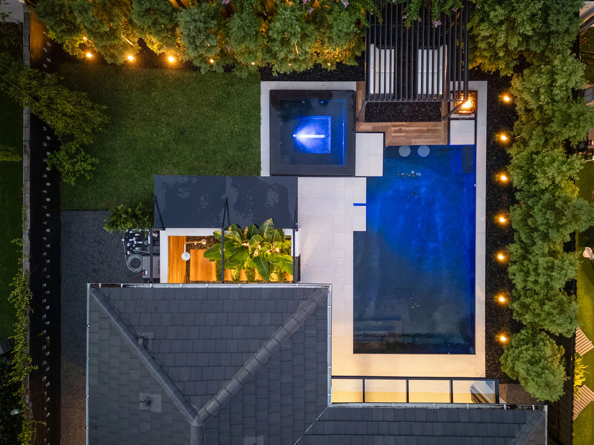 Night aerial view of the illuminated pool and roofscape.