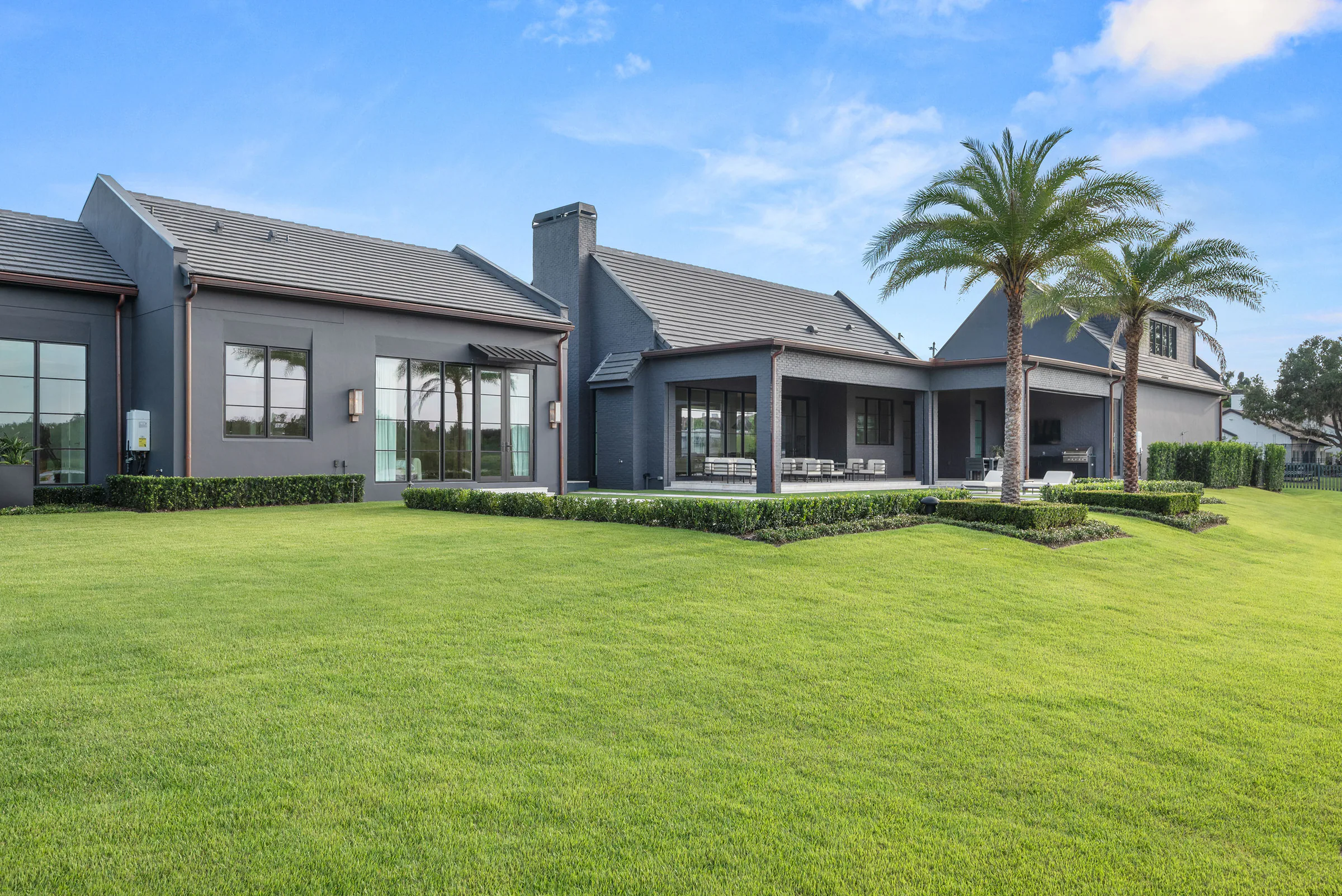 Rear elevation and long rectangular pool viewed across the lawn.