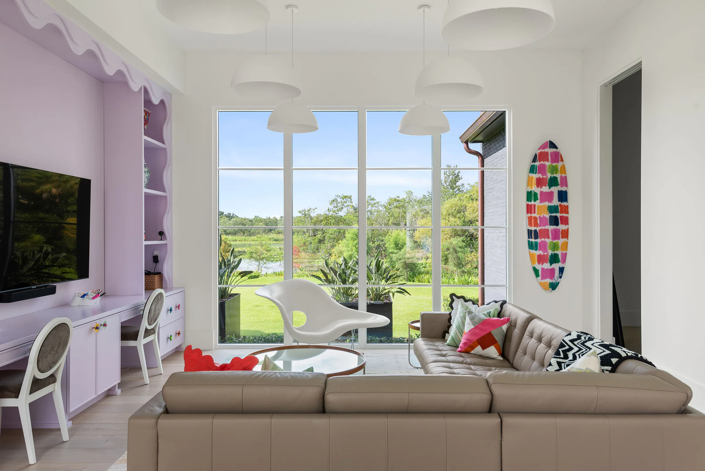 Children's playroom with lavender built-ins, a television wall, curved sofa and stained-glass window.