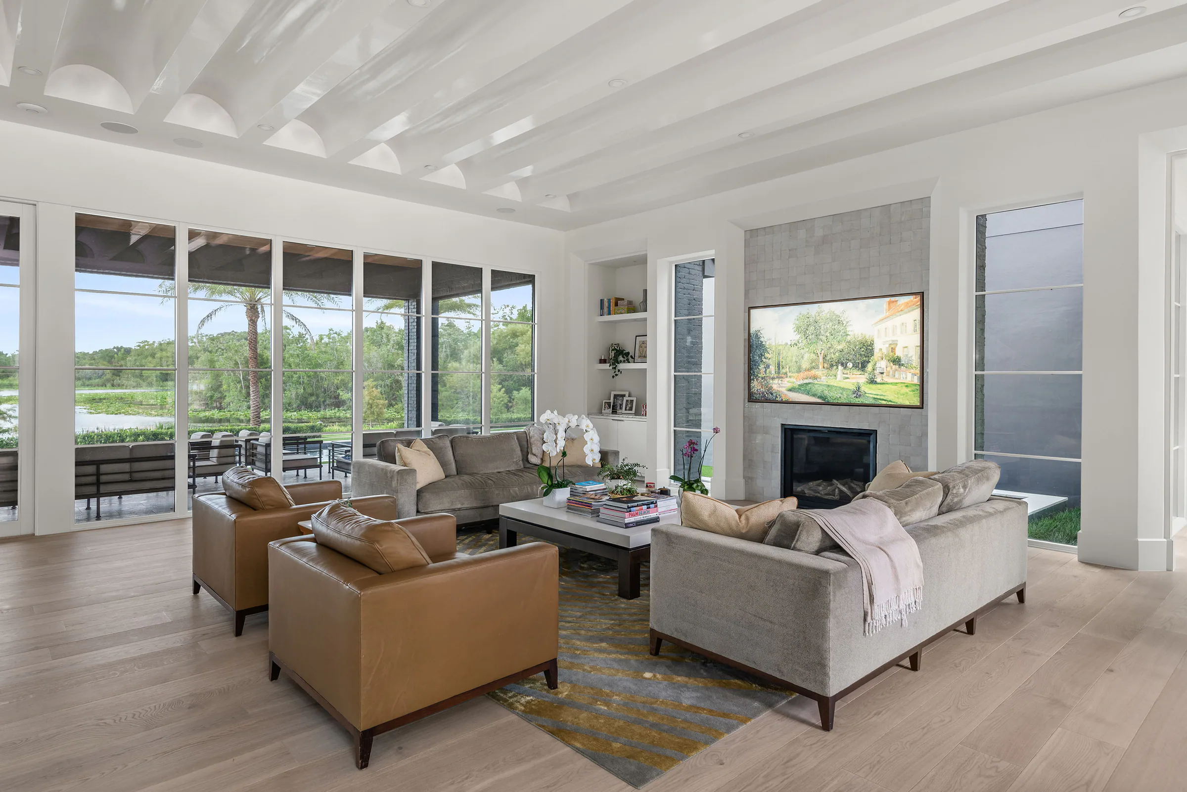 Living room with a dark fireplace, built-in shelving and soft seating beside tall windows.