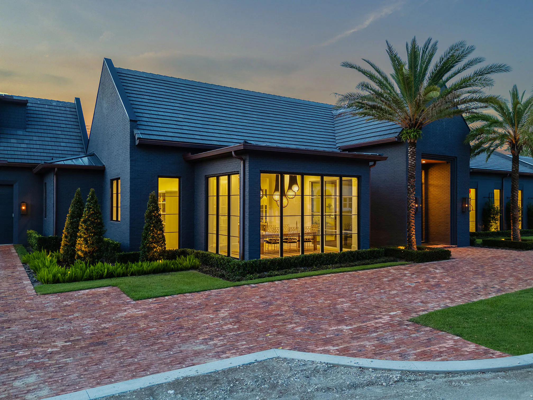 Front corner of Manor at blue hour with warm light behind the tall black-framed windows.