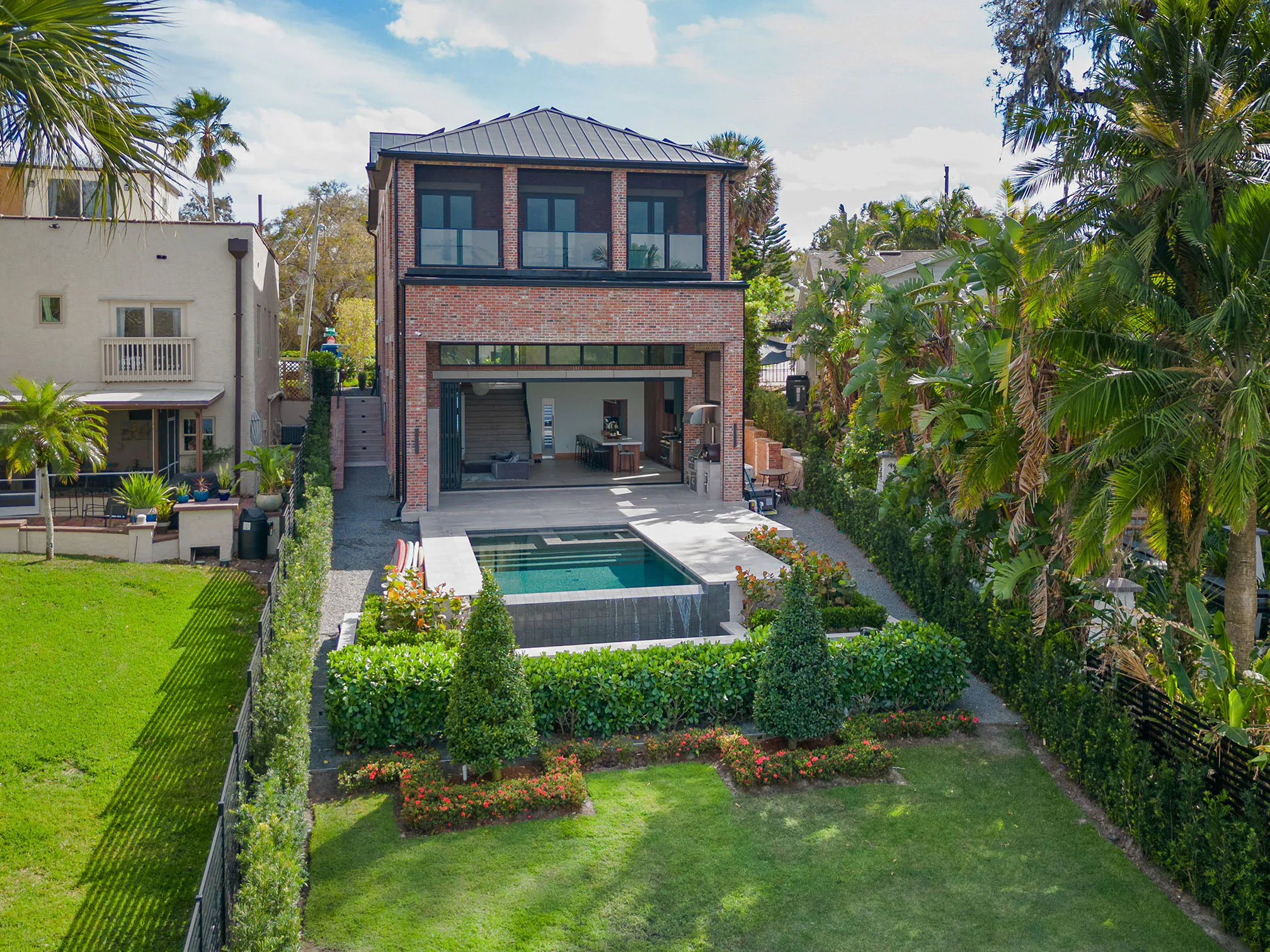 Rear elevation and pool framed by palms and lawn.