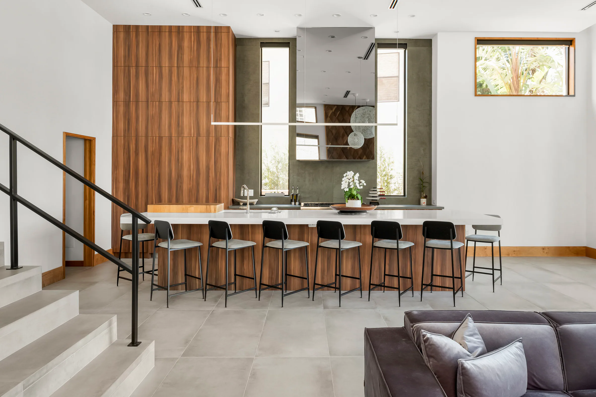 Kitchen island with wood cabinetry and dark counter stools. Terrace, a custom home by Rare Builders in Orlando.