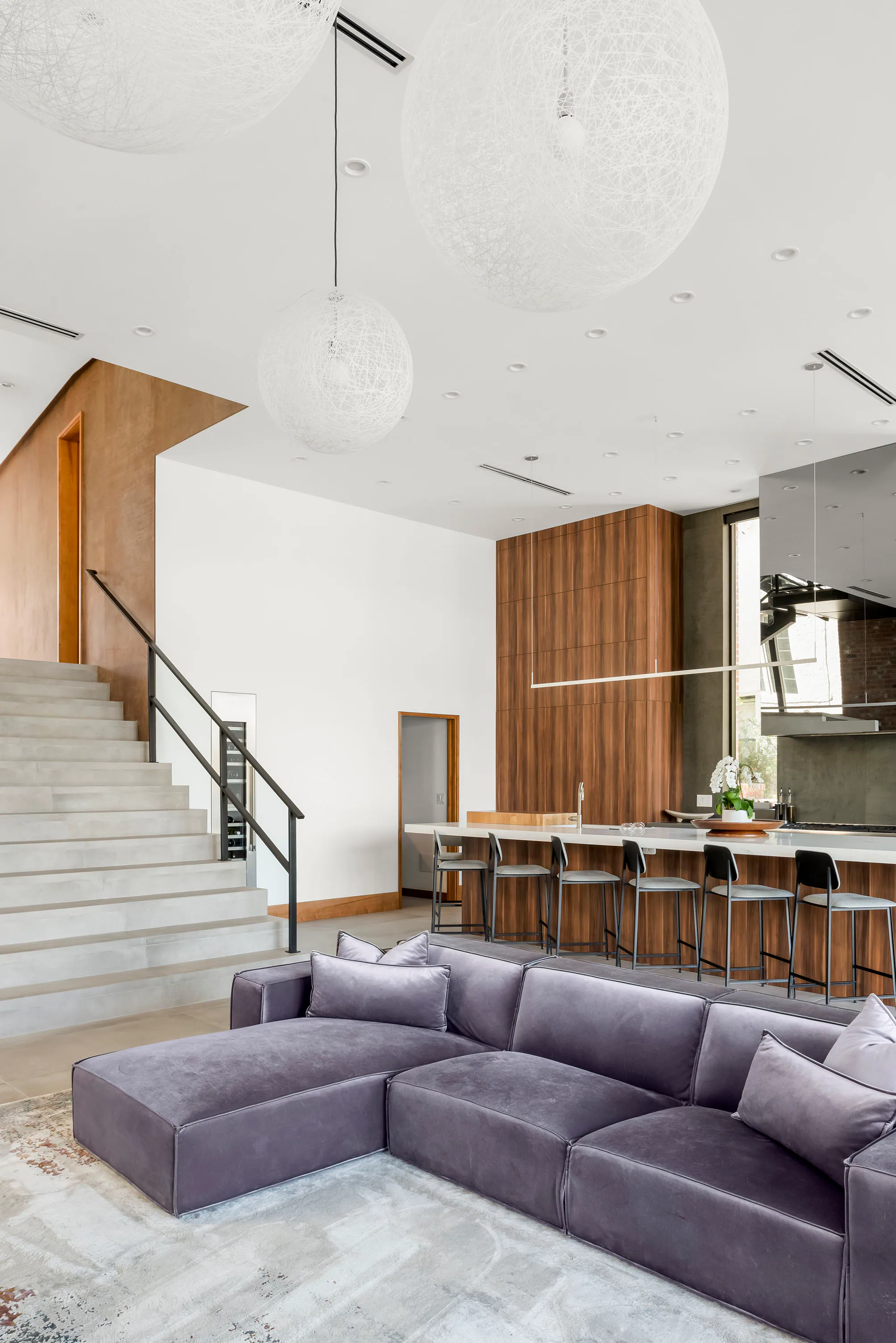 Living room with pale sectional seating beside the open kitchen. Terrace, a custom home by Rare Builders in Orlando.