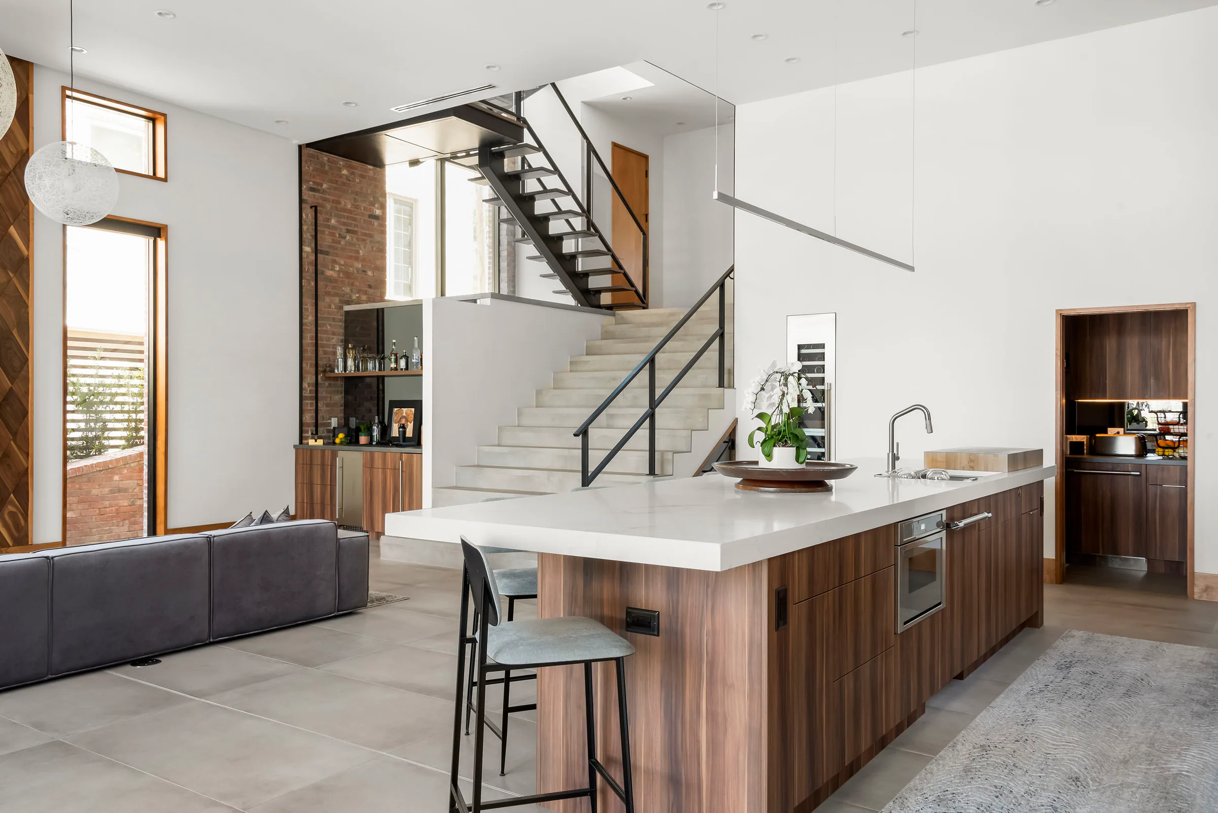 Kitchen island and pale stone worktop beside wood cabinetry. Terrace, a custom home by Rare Builders in Orlando.