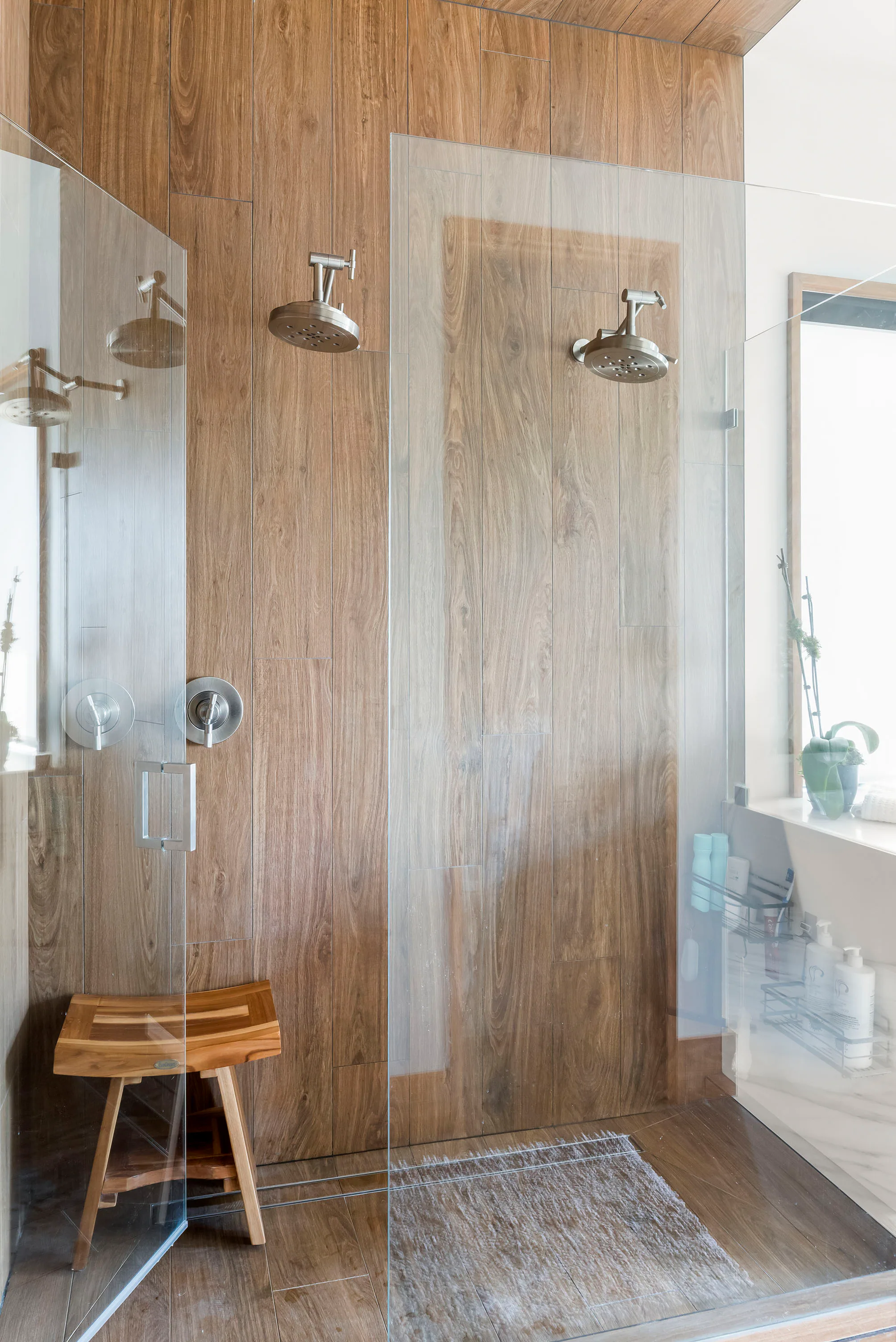 Glass shower lined with warm stone tile. Terrace, a custom home by Rare Builders in Orlando.
