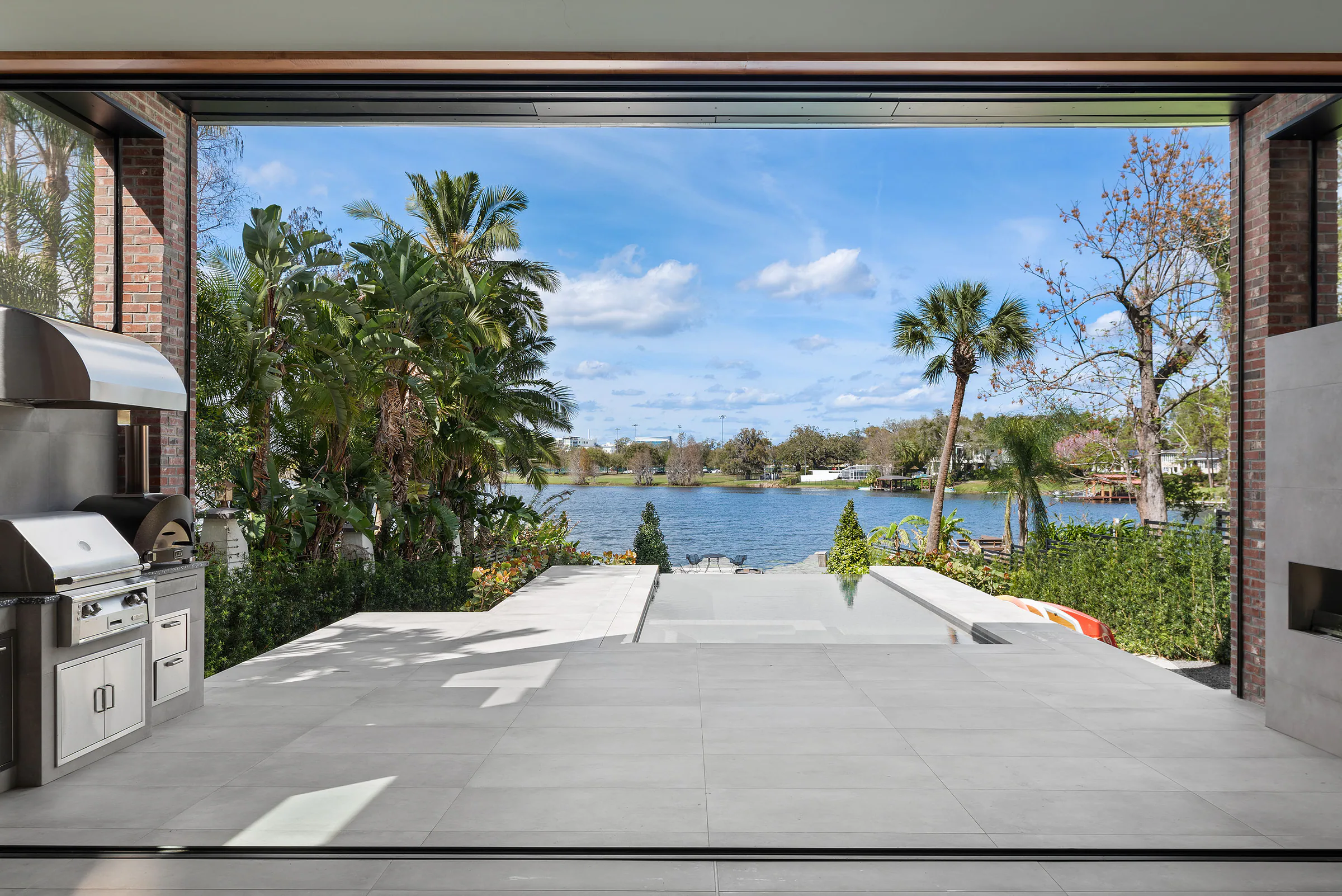 Florida Room opening directly to the terrace and the lake beyond. Terrace, a custom home by Rare Builders in Orlando.